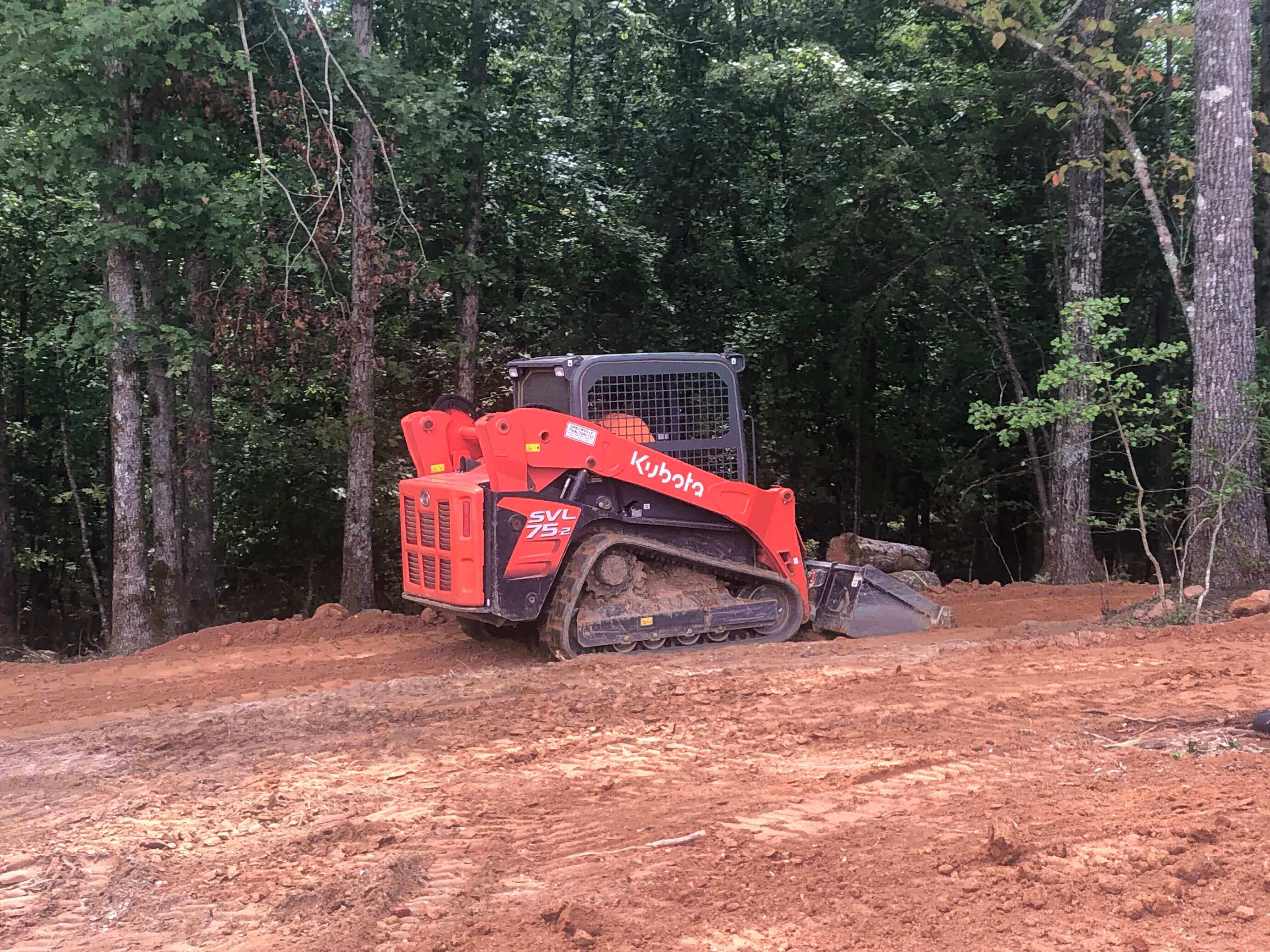a kubota skid steer loader being used to clear a site